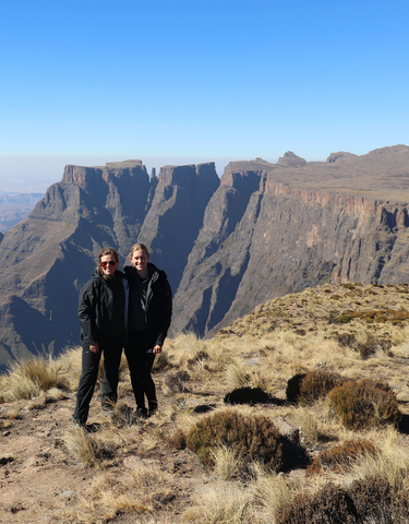 Two people posing at a mountain viewpoint with a dramatic landscape.