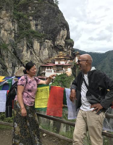 People talking in front of Paro Taktsang nestled in the mountains.