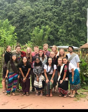 Group of people posing together outdoors, dressed in traditional patterns.