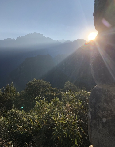 Sun shining over a mountainous landscape.