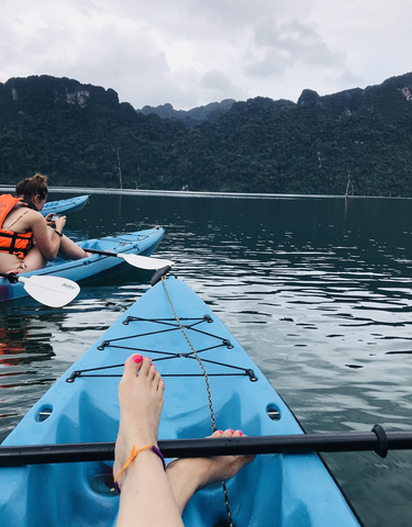 Kayaks on a lake with a person in a life jacket taking a photo.