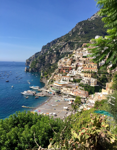 Picturesque view of colorful cliffside buildings overlooking the sea with boats docked below.