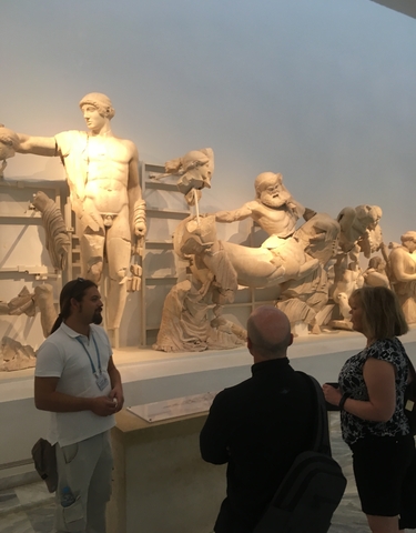 Visitors viewing classical Greek statues in a museum.