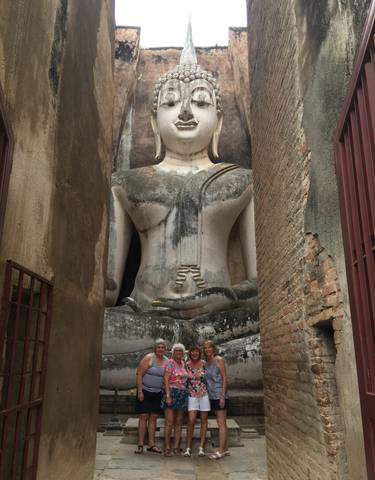 Large seated Buddha statue among ancient bricks.