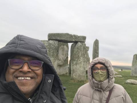 Two people wearing jackets near Stonehenge.