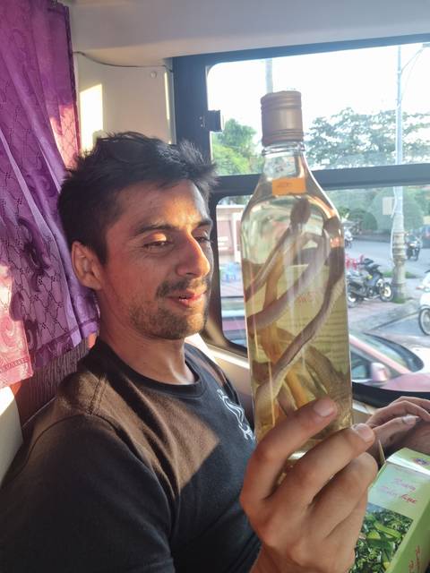 Man holding a bottle of liquor inside a vehicle.