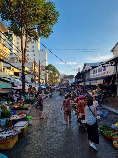       Busy outdoor market scene with vendors and customers.
  