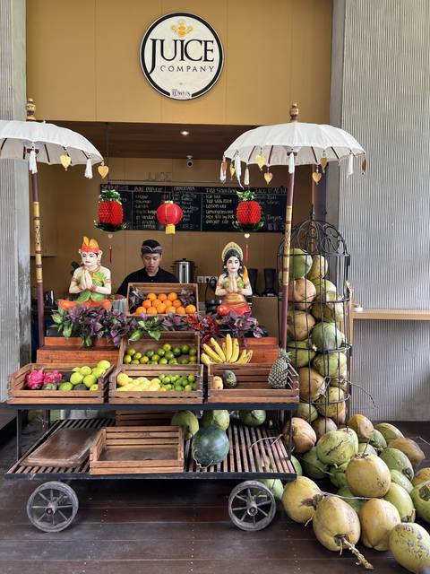      Person standing near a fruit juice stand with various fruits displayed.
  