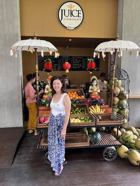       Person standing in front of a fruit juice stand with various fruits.
  