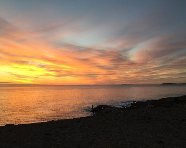       Sunset view over a calm ocean with colorful sky.
  