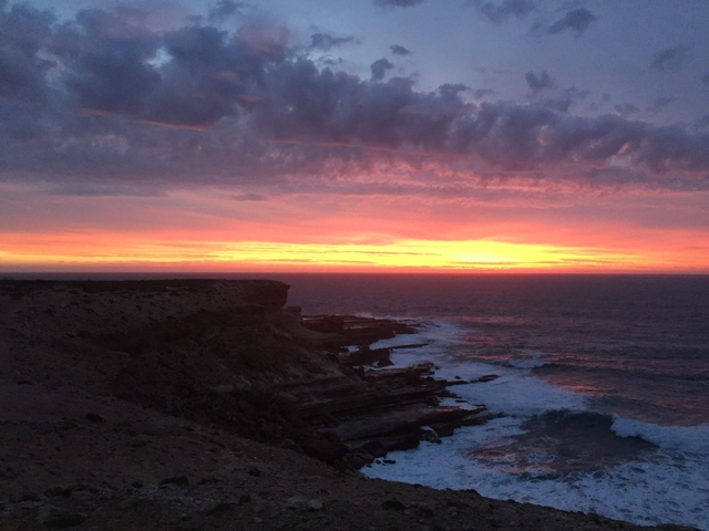       Vibrant sunset view over a rocky shoreline.
  