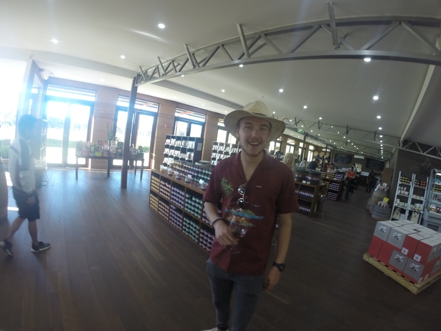       Person smiling inside a shop with products on shelves.
  