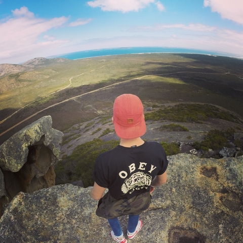       Person looking over a vast landscape from a rocky outcrop.
  