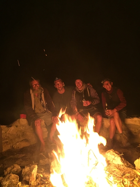       Group of friends around a campfire at night enjoying themselves.
  