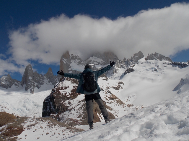       Person joyfully reaching out towards towering snowy peaks.
  