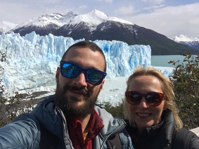       Two people in front of a glacier wearing sunglasses.
  