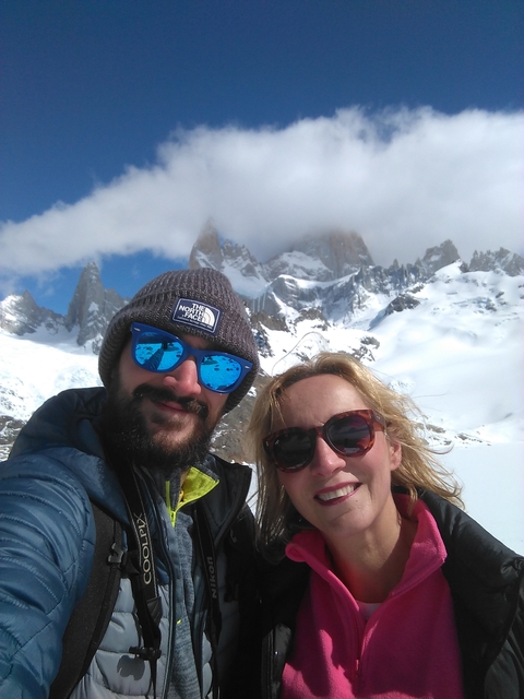       Selfie of two people in front of snow-covered mountains.
  