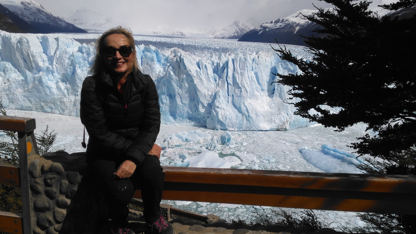       Person posing in front of a large glacier.
  
