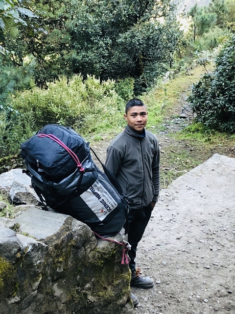 Person standing on a rocky path with a large backpack.