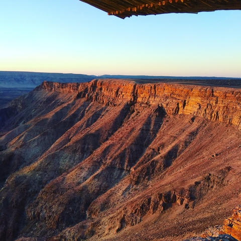       Stunning view of a canyon at sunset with rugged cliffs.
  