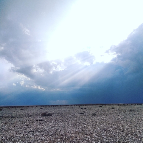       Rays of sunlight breaking through clouds over a vast landscape.
  