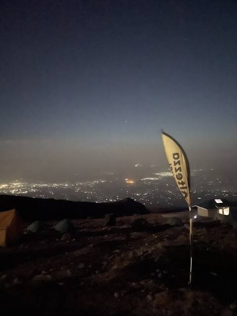 Flagpole with a city view at night.
