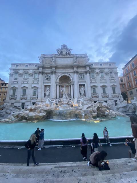       People gathered around a famous fountain.
  
