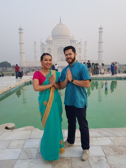 Two people in traditional attire posing in front of the Taj Mahal.
