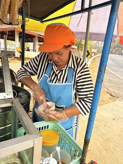 Street vendor preparing food at a roadside stand.