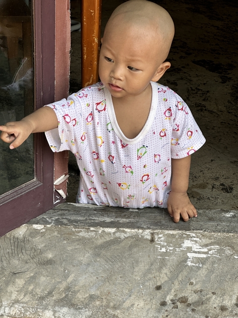 Young child standing at a window with patterned clothing.