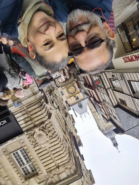 Two people in front of a historic building with a clock tower.