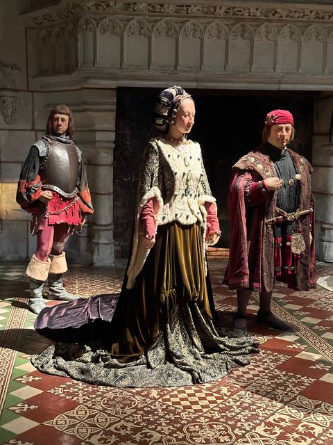 Historical characters in period costumes in a chateau.