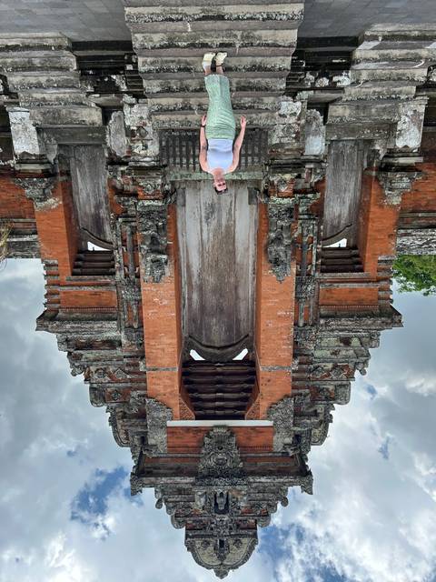 Person posing at the gates of a temple.