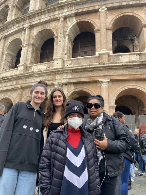       Group of people in front of a large stone structure.
  