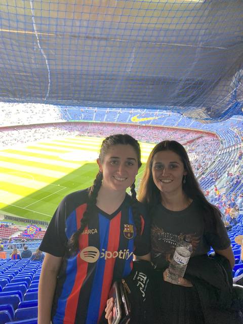 Two people posing at an outdoor sports stadium.