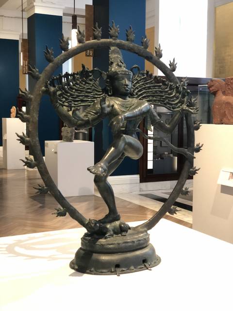       Metal statue of a dancing figure in a circular frame.
  