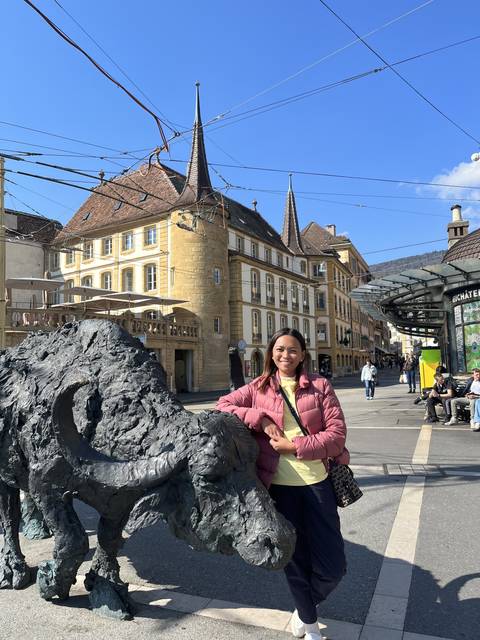 Person standing next to a statue in a city center.