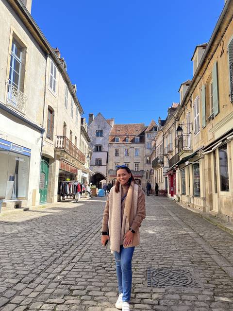 Individual posing in a quaint cobblestone street.