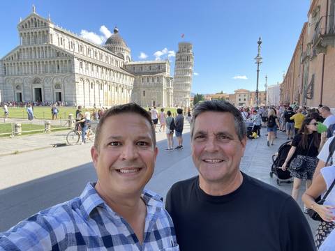 Two men posing with the Leaning Tower of Pisa in the background.