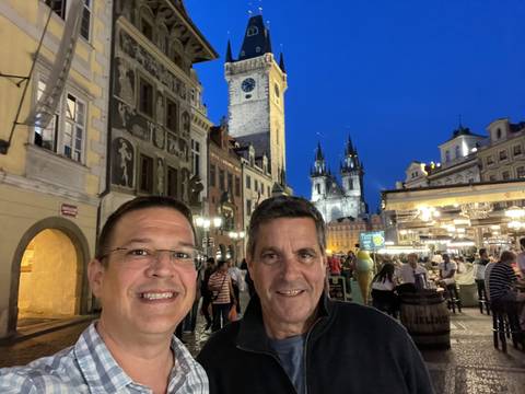 Two people in Prague at evening, with a clock tower.