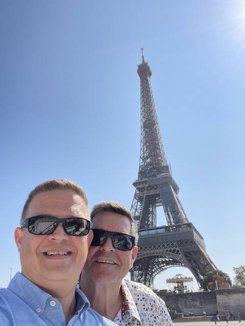 Two men smiling with the Eiffel Tower in the background.