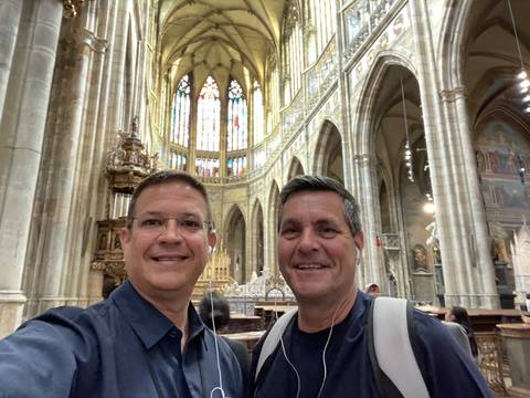 Two men inside a cathedral with stained glass windows.