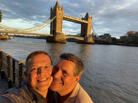 Two men with Tower Bridge in the background at sunset.