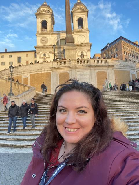       Person in front of a historical stairway in a city.
  