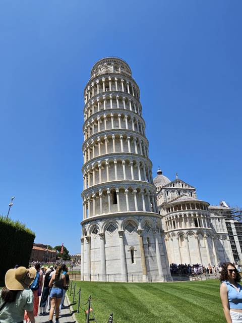       The Leaning Tower of Pisa with tourists nearby.
  