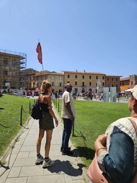       Tourists walking in Pisa with a historic building nearby.
  
