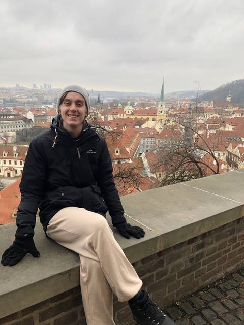 Person sitting on a ledge with an expansive view of a city.