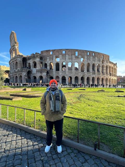 Person posing in front of the Colosseum.