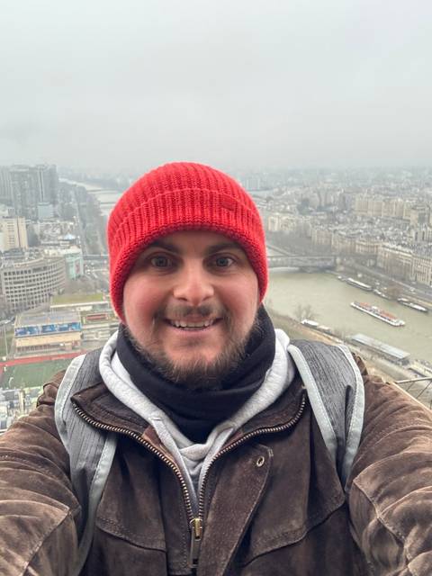 Person with a red beanie overlooking a city river.