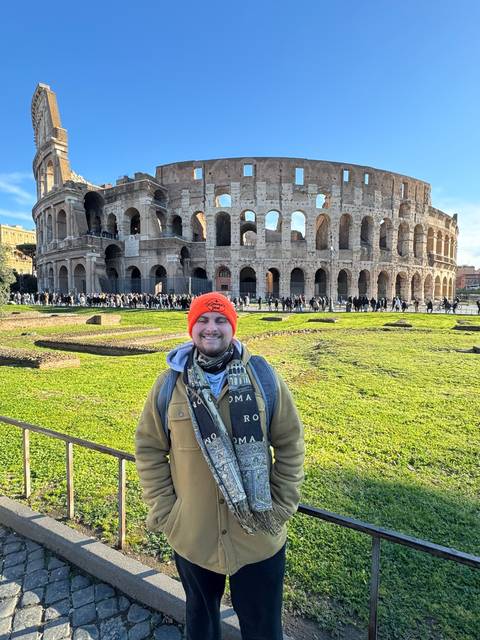 Person lying down with the Colosseum in the background holding a can.